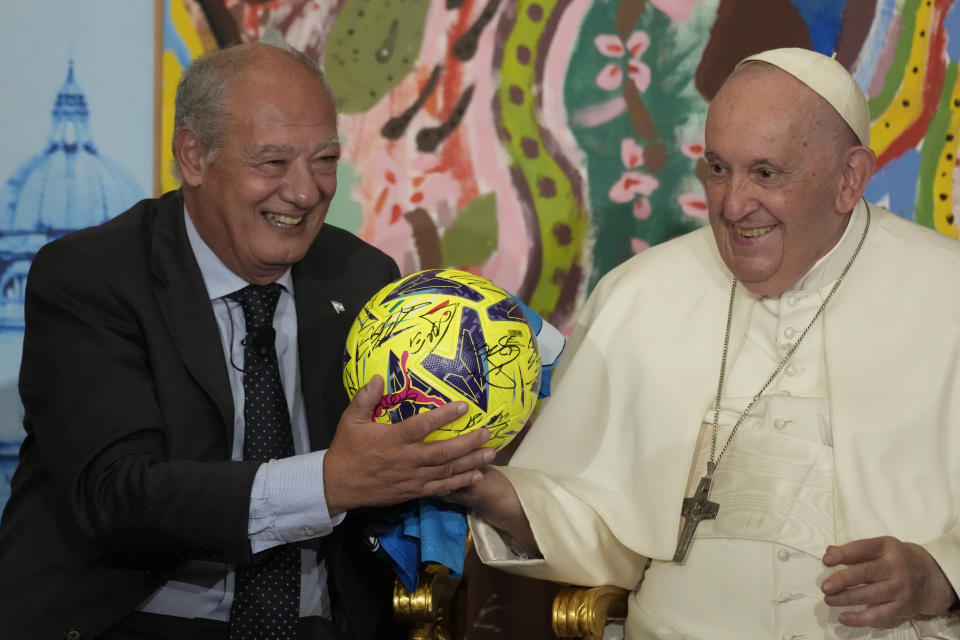 Pope Francis, flanked by José María del Corral, president of Scholas Occurrentes, holds a soccer ball he was gifted as they attend the world's first meeting of the 'Educational Eco-Cities' promoted by the 'Scholas Occurrentes', at the Vatican, Thursday, May 25, 2023. (AP Photo/Andrew Medichini)