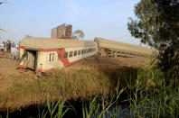 People gather at the site where a passenger train derailed injuring at least 100 people, near Banha, Qalyubia province, Egypt, Sunday, April 18, 2021. At least eight train wagons ran off the railway, the provincial governor's office said in a statement. (AP Photo/Tarek Wagih)