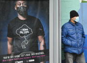 A man wearing a protective mask waits for a city bus during the COVID-19 pandemic in Toronto on Tuesday, Dec. 1, 2020. Toronto and Peel region continue to be in lockdown. (Nathan Denette/The Canadian Press via AP)