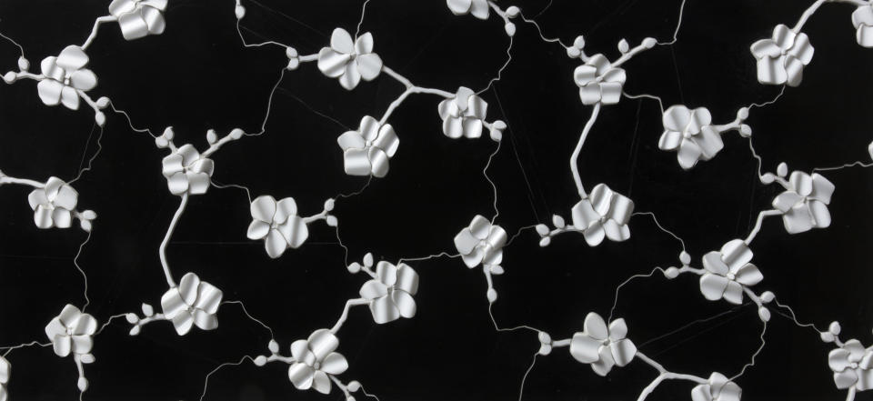 This photo provided by Artistic Tile shows Michael Aram's orchid design transformed into a striking three dimensional ceramic tile by Artistic Tile. The tile has dozens of hand formed flowers on a black or white background. The pattern is also available in a 2D version for floors and other purposes. Artistic Tile via AP)