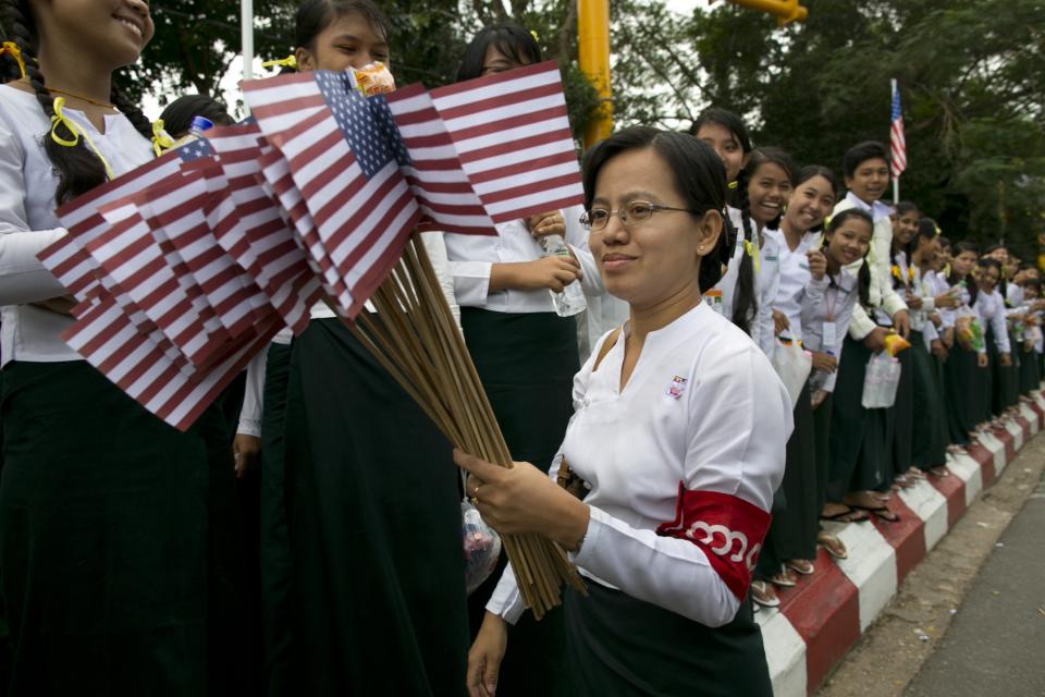 YANGON, MYANMAR - NOVEMBER 19: A Burmese teacher holds American flags as students line the streets to welcome US President Barack Obama as arrives at Yangon International airport during his historical first visit to the country on November 19, 2012 in Yangon, Myanmar. Obama is the first US President to visit Myanmar while on a four-day tour of Southeast Asia that also includes Thailand and Cambodia. (Photo by Paula Bronstein/Getty Images)
