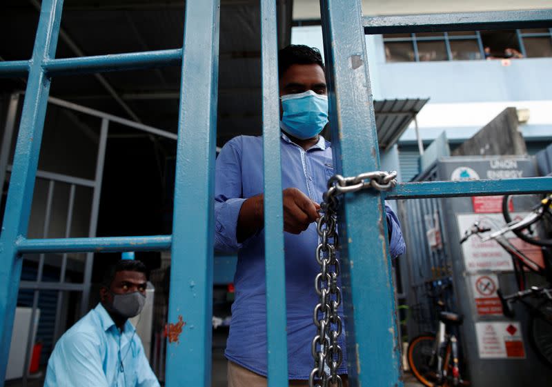 A migrant worker living in a factory-converted dormitory locks the gate of their dormitory as they serve stay-home notices during the coronavirus disease (COVID-19) outbreak in Singapore