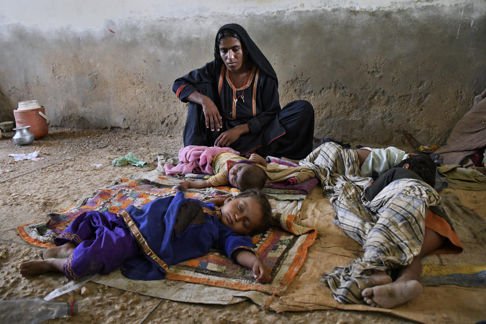 A woman takes care of her children as she with other families sheltering in a school building due to Cyclone Biparjoy approaching, in Golarchi near Badin, Pakistan's southern district in the Sindh province, Wednesday, June 14, 2023. The coastal regions of India and Pakistan were on high alert Wednesday with tens of thousands being evacuated a day before Cyclone Biparjoy was expected to make landfall. (AP Photo/Umair Rajput)