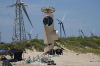 Beachgoers take cover in the shade near wind turbines along the coast of Pingtan in Southern China's Fujian province on Aug. 6, 2022. The world's two biggest emitters of greenhouse gases are sparring on Twitter over climate policy, with China asking if the U.S. can deliver on the landmark climate legislation signed into law by President Joe Biden this week. (AP Photo/Ng Han Guan)