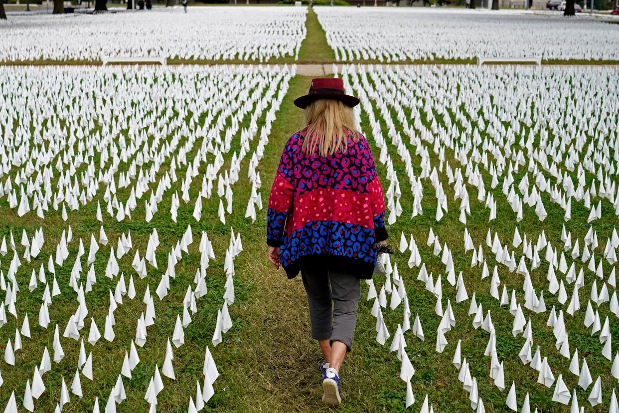 <p>Artist Suzanne Brennan Firstenberg walks among thousands of white flags planted in remembrance of Americans who have died of Covid-19 in Washington DC. The U.S. death toll from the coronavirus topped 300,000 on 14 December as the first doses of a vaccine became available.</p> (AP)