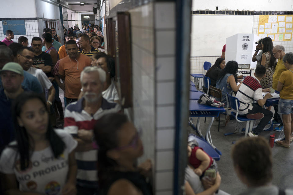 People wait in line to vote in the general election at a polling station in the Mare Complex slum in Rio de Janeiro, Brazil, Sunday, Oct. 7, 2018. Brazilians choose among 13 candidates for president Sunday in one of the most unpredictable and divisive elections in decades. If no one gets a majority in the first round, the top two candidates will compete in a runoff. (AP Photo/Leo Correa)
