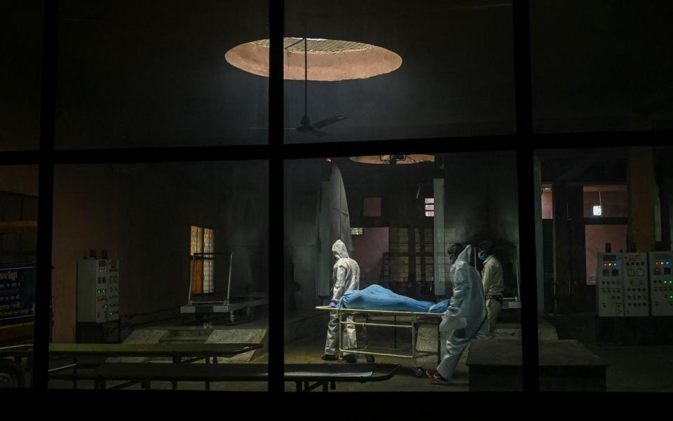 Ambulance staff wearing personal protective equipment suits carry the dead body of a person, who died due to the coronavirus, inside a crematorium - Prakash SINGH / AFP