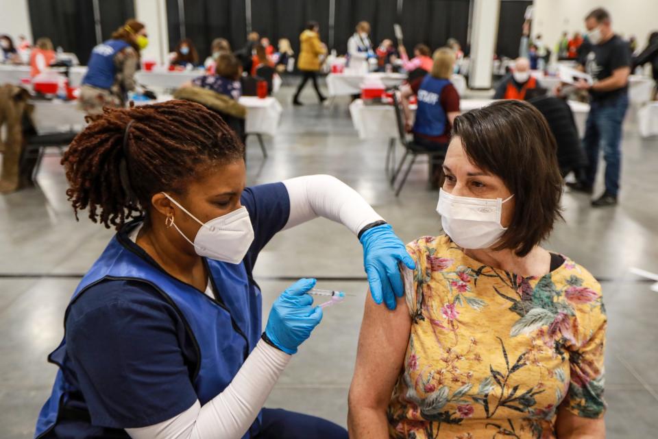 Cynthia Krencicki, 58, of Livonia receives the Moderna COVID-19 vaccination from the Oakland County Health Division Vaccinator Khalia Hill, 40, of Pontiac, Mich. at Suburban Showplace in Novi, Mich. on Jan. 23, 2021.  Krencicki teaches 2nd grade at Ferndale's Lower Elementary and says she is allergic to Penicillin and has to wait 30 minutes in Observation after receiving her vaccine.