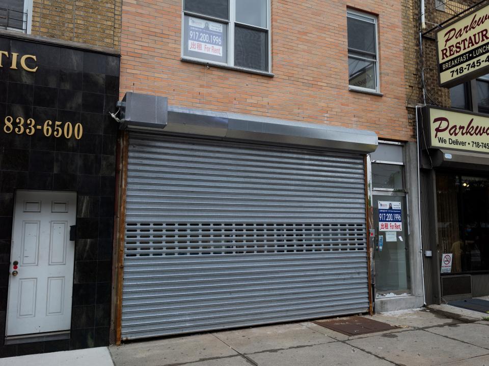 A grey gate covers an empty storefront.