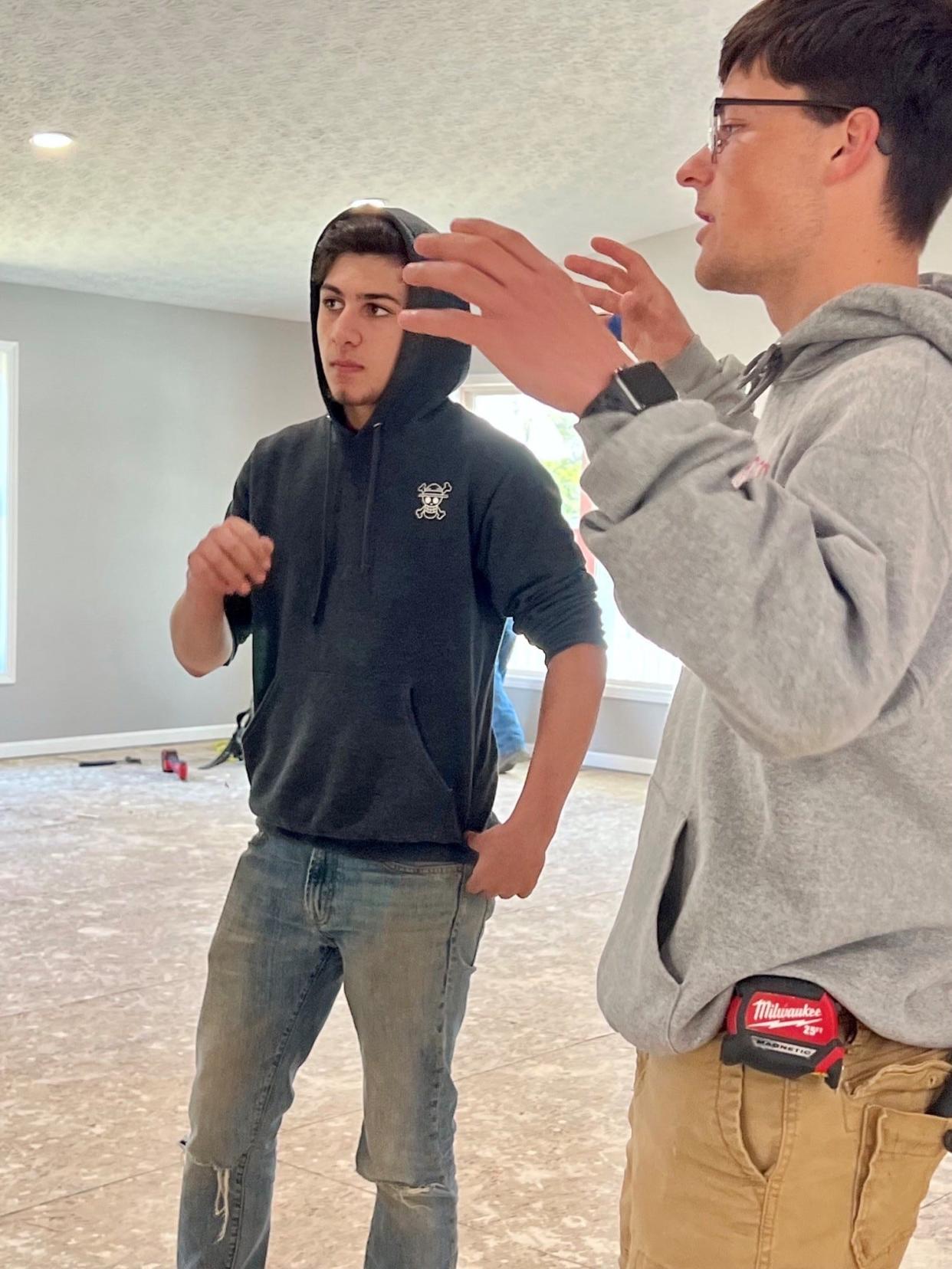 Copley High School student Mohamad Husein, left, and Norton High School student Braden Sullivan talk about the Wadsworth home they are working on in the Four Cities Compact carpentry program on April 29.