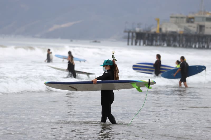 A woman walks into the surf at The Black Girls Surf paddle-out in memory of George Floyd, who died in Minneapolis police custody, in Santa Monica