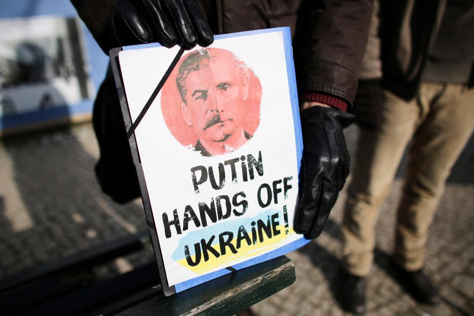 A man holds a poster with half portraits of Soviet leader Joseph Stalin and Russian President Vladimir Putin, during a protest in front of the Russian Embassy in Berlin, Germany, in 2014.