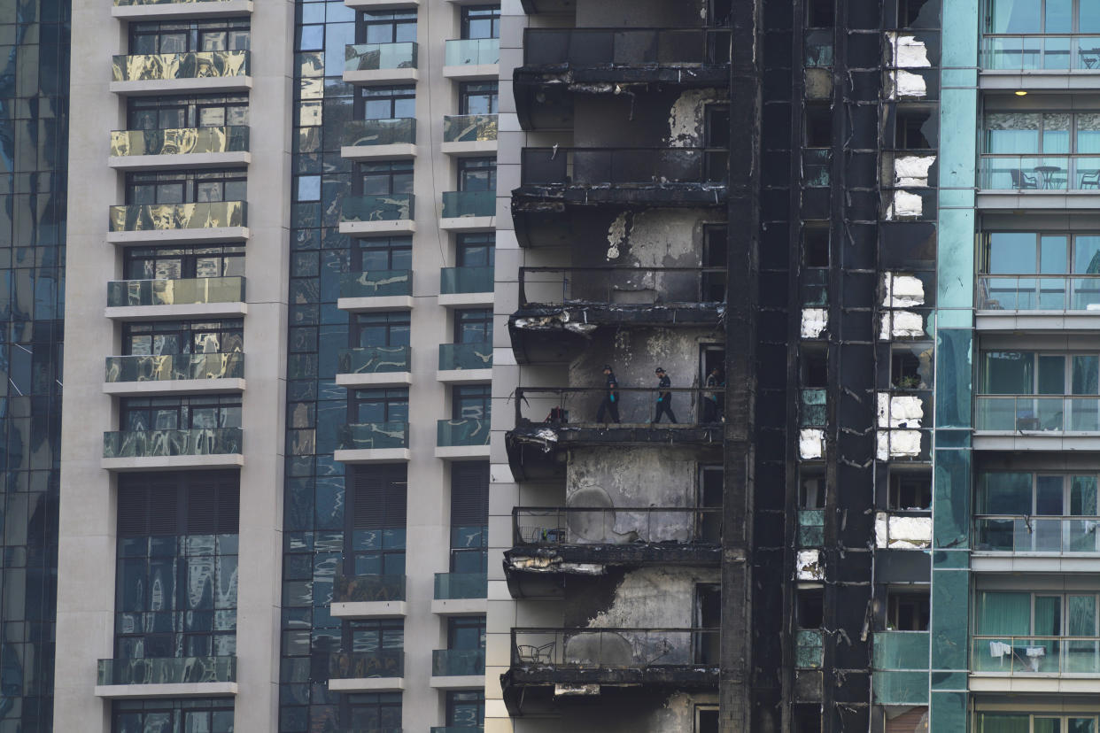 Investigators examine fire damage at the high-rise 8 Boulevard Walk in Dubai, United Arab Emirates, Monday, Nov. 7, 2022. A fire broke out early Monday morning at a 35-story high-rise building in Dubai near the Burj Khalifa, the world's tallest building. (AP Photo/Jon Gambrell)