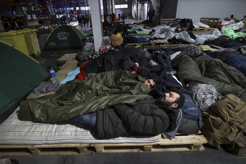 Migrants sleep inside a logistics center at the checkpoint "Kuznitsa" at the Belarus-Poland border near Grodno, Belarus, Sunday, Nov. 21, 2021. The EU says the new surge of migrants on its eastern borders has been orchestrated by the leader of Belarus, President Alexander Lukashenko, in retaliation for EU sanctions placed on Belarus after a government crackdown on peaceful democracy protesters. It calls the move "a hybrid attack'' on the bloc. Belarus denies the charge. (Maxim Guchek/BelTA via AP)