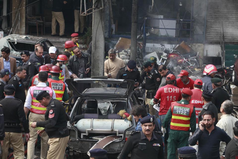 Policemen and residents gather at the site of an explosion outside the police headquarters, in Lahore
