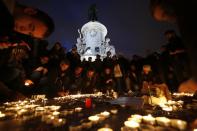 People lay candles during a gathering on the Place de Republique in Paris