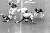 FILE - In this Nov. 25, 1971 file photo, Nebraska's Johnny Rodgers (20) avoids Oklahoma defenders as he returns a punt for a touchdown in the first quarter of an NCAA college football game in Norman, Okla. The game, which Nebraska won 35-31, is widely remembered as "The Game of the Century." (Lincoln Journal Star via AP, File)