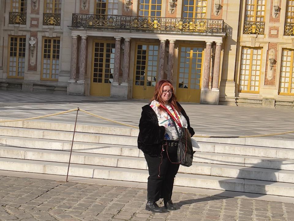 Ashley standing in front of beige Versailles in front of steps