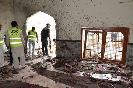 Rescue workers and a policeman stand at the site of an explosion in a Shi'ite mosque in Shikarpur, located in Pakistan's Sindh province January 30, 2015. REUTERS/Amir Hussain