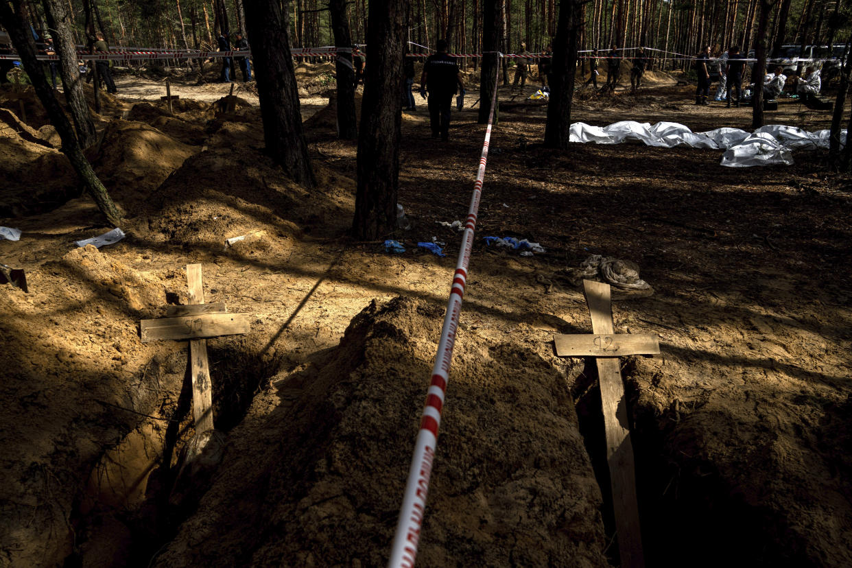 Unidentified graves of civilians and Ukrainian soldiers in a cemetery during an exhumation in the recently retaken area of Izium, Ukraine, Saturday, Sept. 17, 2022. Ukrainian authorities discovered a mass burial site near the recaptured city of Izium that contained hundreds of graves. It was not clear who was buried in many of the plots or how all of them died, though witnesses and a Ukrainian investigator said some were shot and others were killed by artillery fire, mines or airstrikes. (AP Photo/Evgeniy Maloletka)