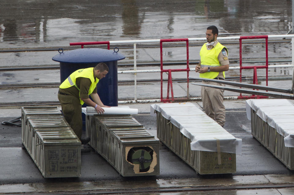 Israeli soldiers cover with plastic to protect from the rain, boxes containing missiles that the military unloaded from the seized Klos-C cargo ship in the military port of the Red Sea resort city of Eilat, southern Israel, Sunday, March 9, 2014. Israel's Prime Minister Benjamin Netanyahu is calling on the European Union's foreign policy chief, Catherine Ashton, currently visiting Tehran, to confront Iranian officials about the weapons Israel says it caught last week en route from Iran to militants in Gaza. Ashton is in Tehran to further negotiations with Iran about its nuclear program. (AP Photo/Ariel Schalit)