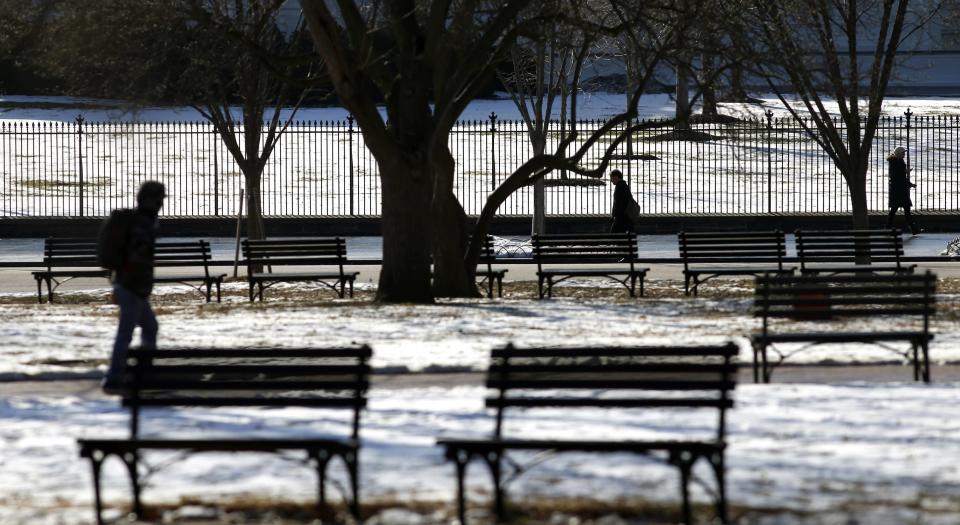 Pedestrians make their way past vacant benches in snowy Lafayette Park in front of the White House in Washington January 27, 2014. Slightly warmer temperatures today provided the nation's capital a brief respite from a recent cold snap. Cold weather is forecast to return by the end of the day. REUTERS/Kevin Lamarque (UNITED STATES - Tags: ENVIRONMENT SOCIETY)