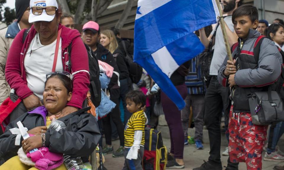 Members of a caravan of Central Americans wait at Tijuana on the Mexico-US border. The boy at right is holding a Honduran flag.