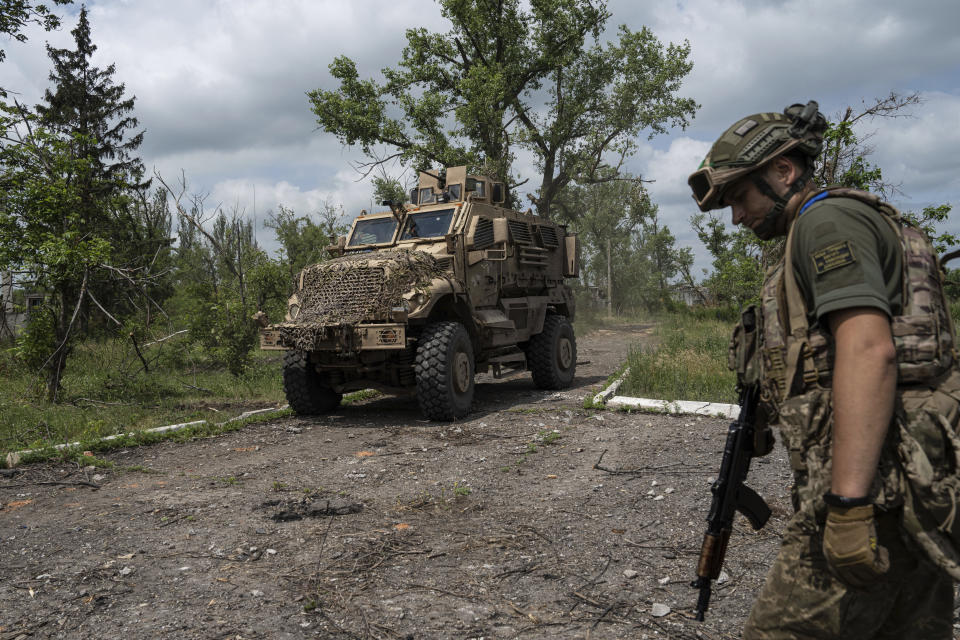 A Ukrainian serviceman of 68th Oleksa Dovbush hunting brigade patrols a street in the recently retaken village of Blahodatne, Ukraine, Saturday, June 17, 2023. (AP Photo/Evgeniy Maloletka)