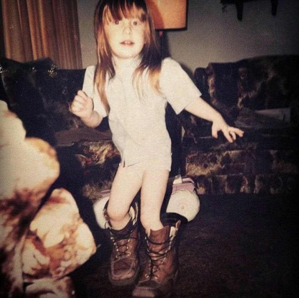 Young child with long hair and wearing adult lace boots
