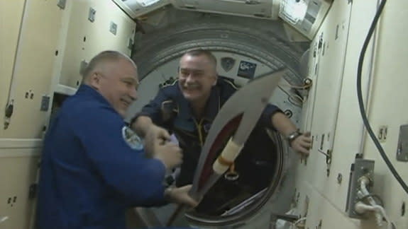Russian cosmonaut Mikhail Tyurin hands off the Olympic torch to Fyodor Yurchikhin as Tyurin comes aboard the International Space Station on Nov. 7, 2013.