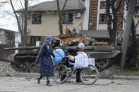 FILE - Local civilians walk past a tank destroyed during heavy fighting in an area controlled by Russian-backed separatist forces in Mariupol, Ukraine, April 19, 2022. (AP Photo/Alexei Alexandrov, File)