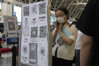 A passenger looks at a board with QR codes for health screening from different provinces at the Beijing Capital Airport terminal 2 in Beijing on Wednesday, June 17, 2020. The Chinese capital on Wednesday canceled more than 60% of commercial flights and raised the alert level amid a new coronavirus outbreak, state-run media reported. (AP Photo/Ng Han Guan)