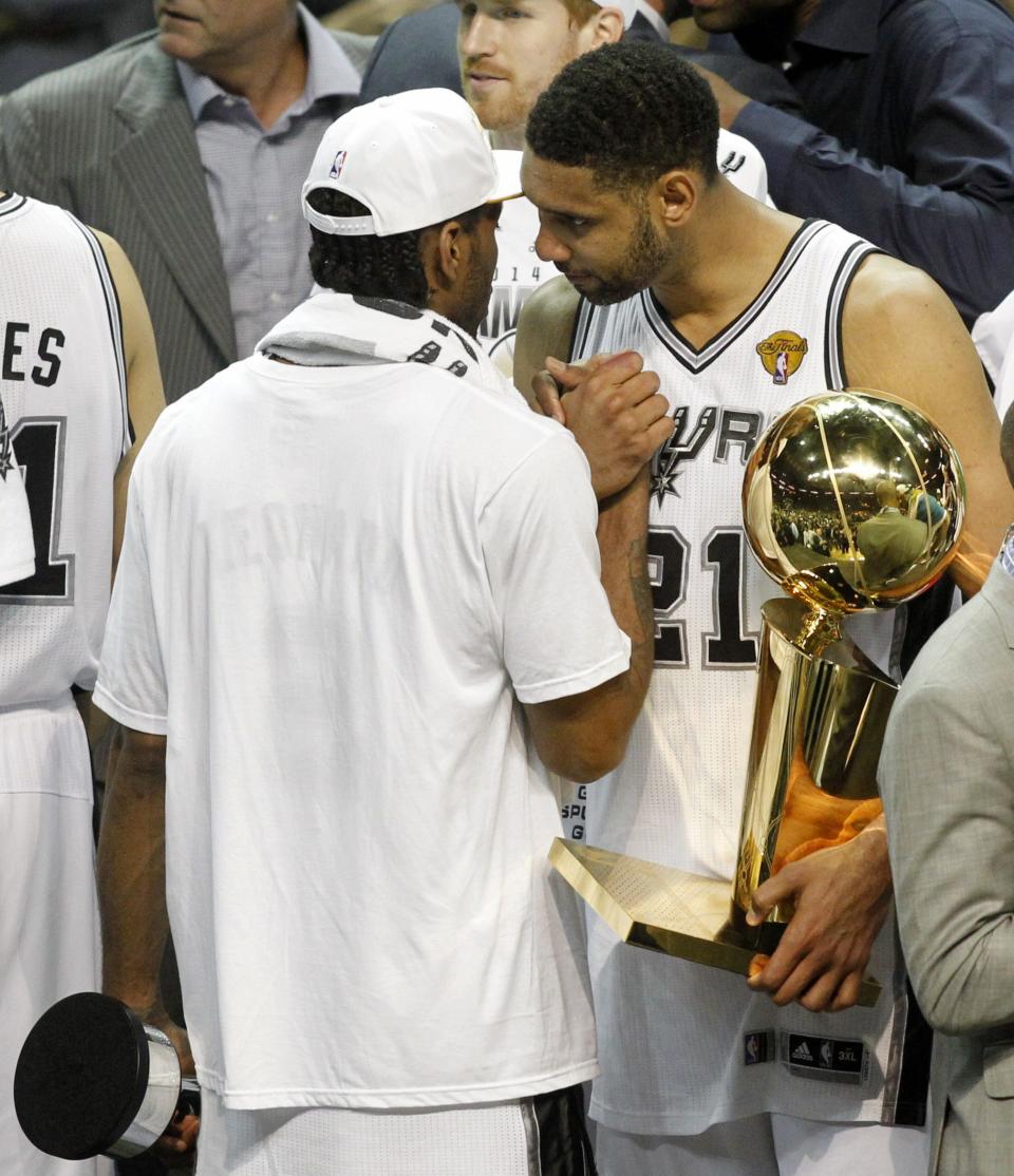 San Antonio Spurs' Tim Duncan (R) holds the Larry O'Brien trophy as he congratulates MVP Kawhi Leonard after the Spurs defeated the Miami Heat in Game 5 of their NBA Finals basketball series in San Antonio, Texas, June 15, 2014. REUTERS/Mike Stone (UNITED STATES - Tags: SPORT BASKETBALL)