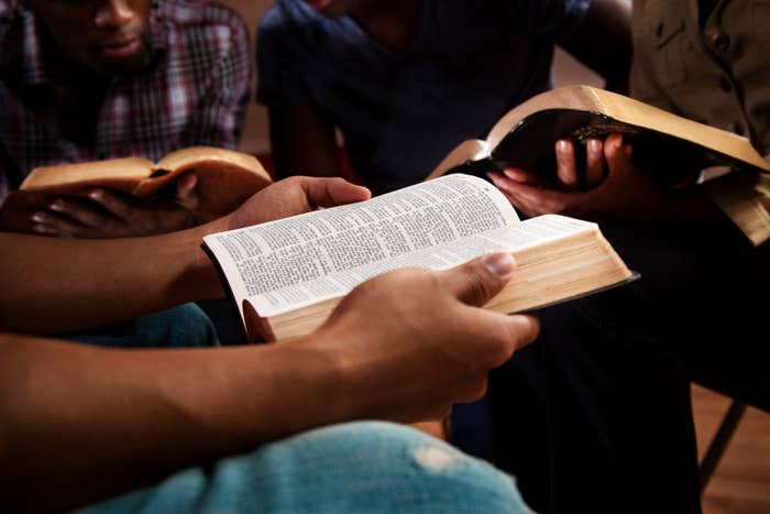 People sitting together, holding and reading open books, focusing on text