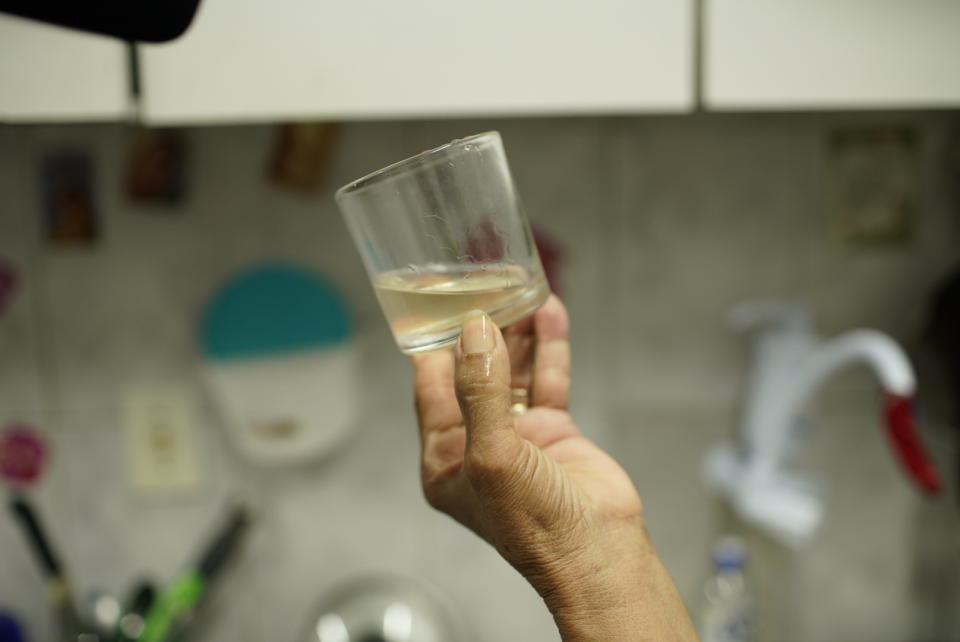 Maria Lina dos Santos shows a glass of cloudy, foul-tasting and smelling water in her home in the Complexo de Alemao slum of Rio de Janeiro, Brazil, Thursday, Jan.16, 2020. Dos Santos said cloudy water isn't unusual in her community, but police are investigating workers at a state utility after smelly tap water flowed into dozens of neighborhoods of the Brazilian city. (AP Photo/Ricardo Borges)