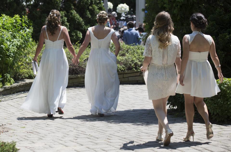 Couples walk down a pathway to the "The Celebration of Love", a grand wedding where over 100 LGBT couples will get married, at Casa Loma in Toronto