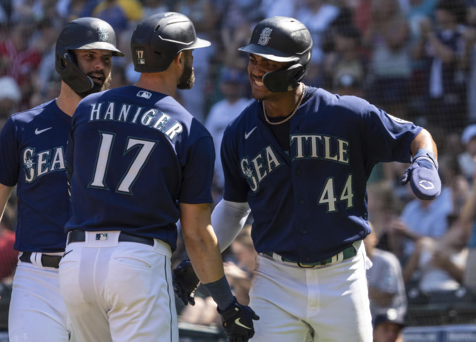 Seattle Mariners' Mitch Haniger, center, is congratulated by Jesse Winker, left, and Julio Rodriguez after hitting a three-run home run off Cleveland Guardians starting pitcher Triston McKenzie during the first inning of a baseball game, Thursday, Aug. 25, 2022, in Seattle. (AP Photo/Stephen Brashear)