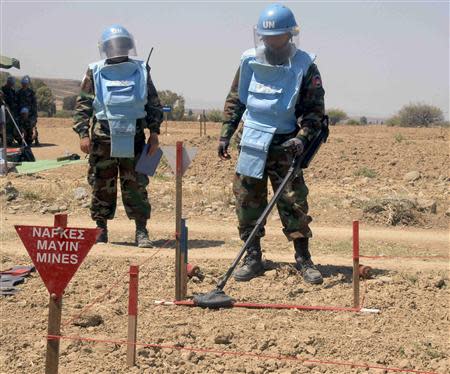 A Cambodian mine clearing expert uses a metal detector for explosives in a mine hazard area in the United Nations controlled buffer zone, east of the Cypriot capital Nicosia April 23, 2014. REUTERS/Andreas Manolis