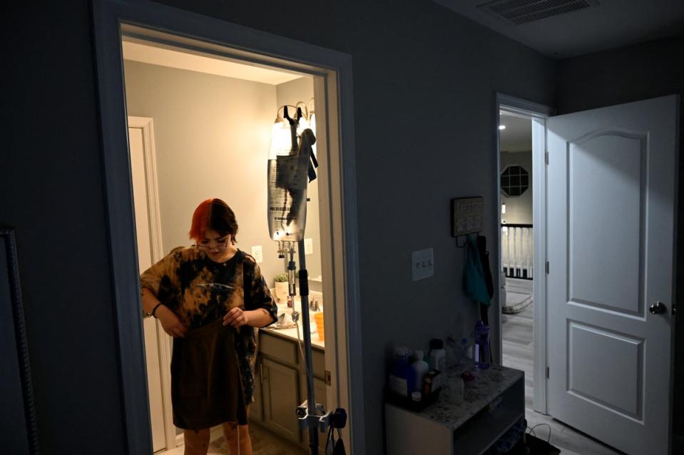 Logan tidies up their room while they carry their IV bag (Reuters)