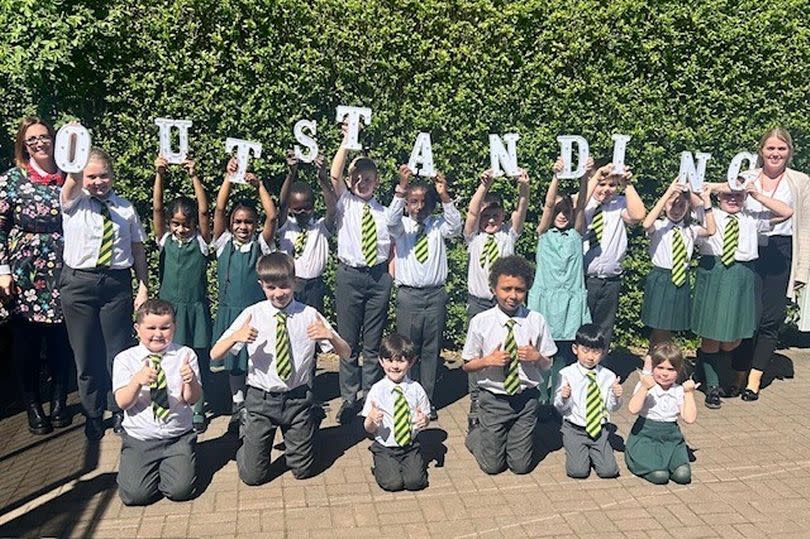 Happy pupils show that they are 'outstanding' at St Joseph's Catholic Primary School - they are spelling out outstanding