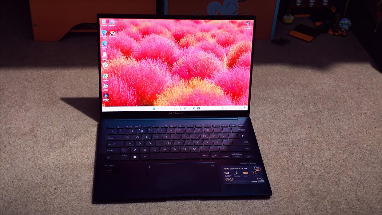  A blue ASUS Zenbook 14 OLED (UX3405) on a carpeted floor. 