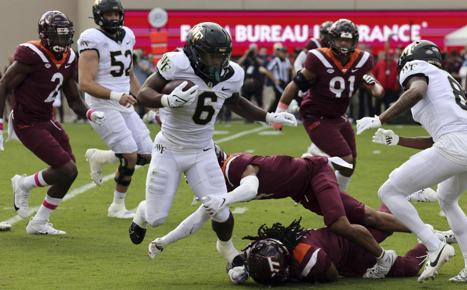 Wake Forest running back Justice Ellison (6) is tackled by Virginia Tech defenders Mansoor Delane (4) top, and Keonta Jenkins (7) in the first quarter of an NCAA college football game in Blacksburg, Va., Saturday, Oct. 14, 2023. (Matt Gentry/The Roanoke Times via AP)