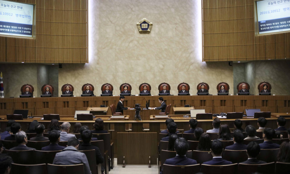 South Korean Chief Justice of the Supreme Court Kim Myeongsu, top center, sits with other justices upon their arrival at the Supreme Court in Seoul, South Korea, Thursday, Nov. 1, 2018. South Korea's top court has ruled that people can legally reject mandatory military service on conscientious or religious grounds and must not be punished. (Yun Dong-jin/Yonhap via AP)