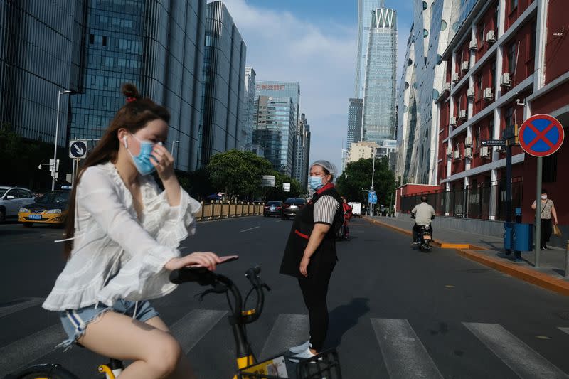 People wearing face masks cross a street, following the coronavirus disease (COVID-19) outbreak, in Beijing's central business area