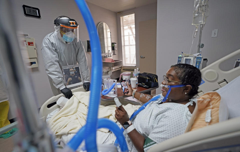 Dr. Joseph Varon, left, talks with LaTanya Robinson during rounds inside the Coronavirus Unit at United Memorial Medical Center, Monday, July 6, 2020, in Houston. Robinson says she was caring for her son when he got the virus. Both she and her husband eventually caught it. While her son and husband's symptoms were relatively mild, she went from feeling tired and struggling to move to hardly being able to breathe. (AP Photo/David J. Phillip)