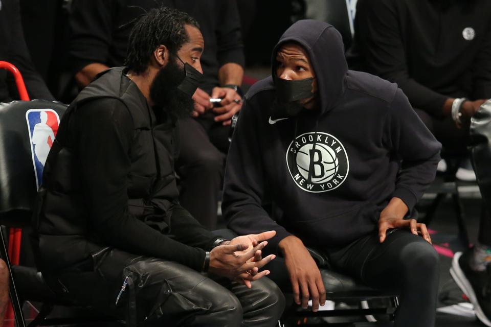 Brooklyn Nets guard James Harden talks on the bench with Kevin Durant during an April 10 game.