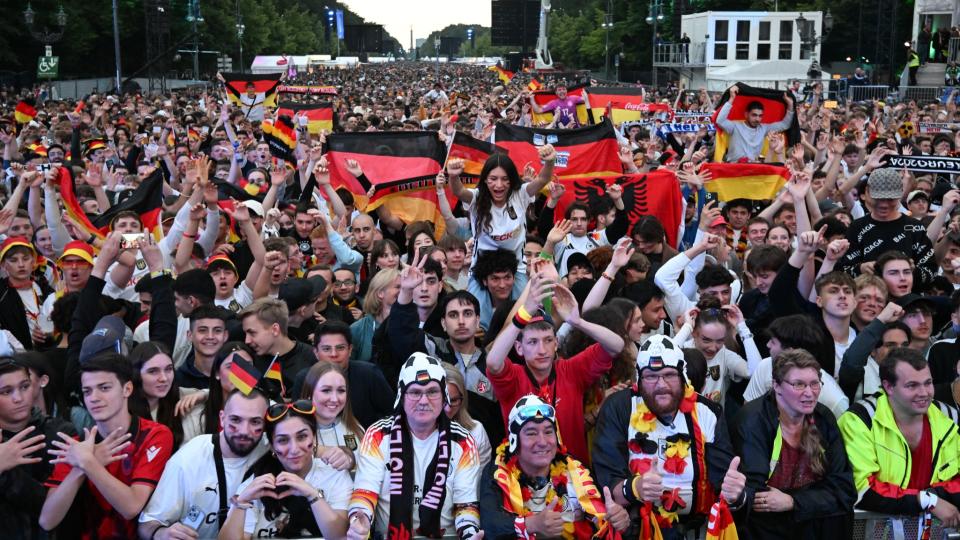 <span>Fußballfans mit Deutschlandfahnen auf der Fanmeile am Brandenburger Tor kurz vor dem Eröffnungsspiel der EM zwischen Deutschland und Schottland am 14. Juni 2024 </span><div><span>RALF HIRSCHBERGER</span><span>AFP</span></div>