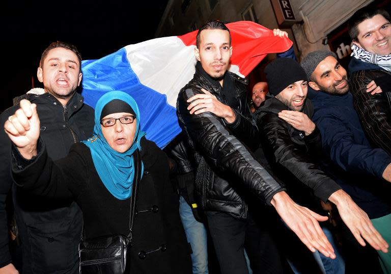 People perform "quenelle" salutes outside the controversial French comic Dieudonne's theatre in Paris on December 28, 2013, while protesting against French Interior minister who called for Dieudonne's new tour performances to be banned