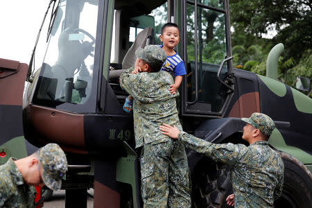 A solider puts a child into a military vehicle during a public fair which displays military equipments, in Taipei, Taiwan September 29, 2018. Picture taken September 29, 2018. REUTERS/Tyrone Siu