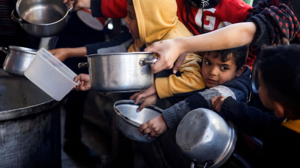 Palestinian children in Rafah wait to receive food distributed by a charity kitchen amid severe food shortages of food supplies. - Mohammed Salem/Reuters